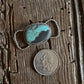 Turquoise stone twilly slide on a wooden surface with a coin for scale