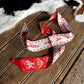 Red and white patterned ribbon on a wooden surface with a cowhide rug in the background