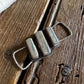 Metallic pendant with three cylindrical elements on a wooden surface