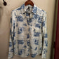 White shirt with blue pattern hanging on a hanger against a beige wall.