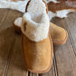 Brown slipper with white fur lining on a wooden surface