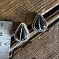 Pair of black and green earrings on a wooden surface with a ruler for scale