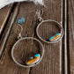 Pair of silver hoop earrings with turquoise stones on a wooden surface.