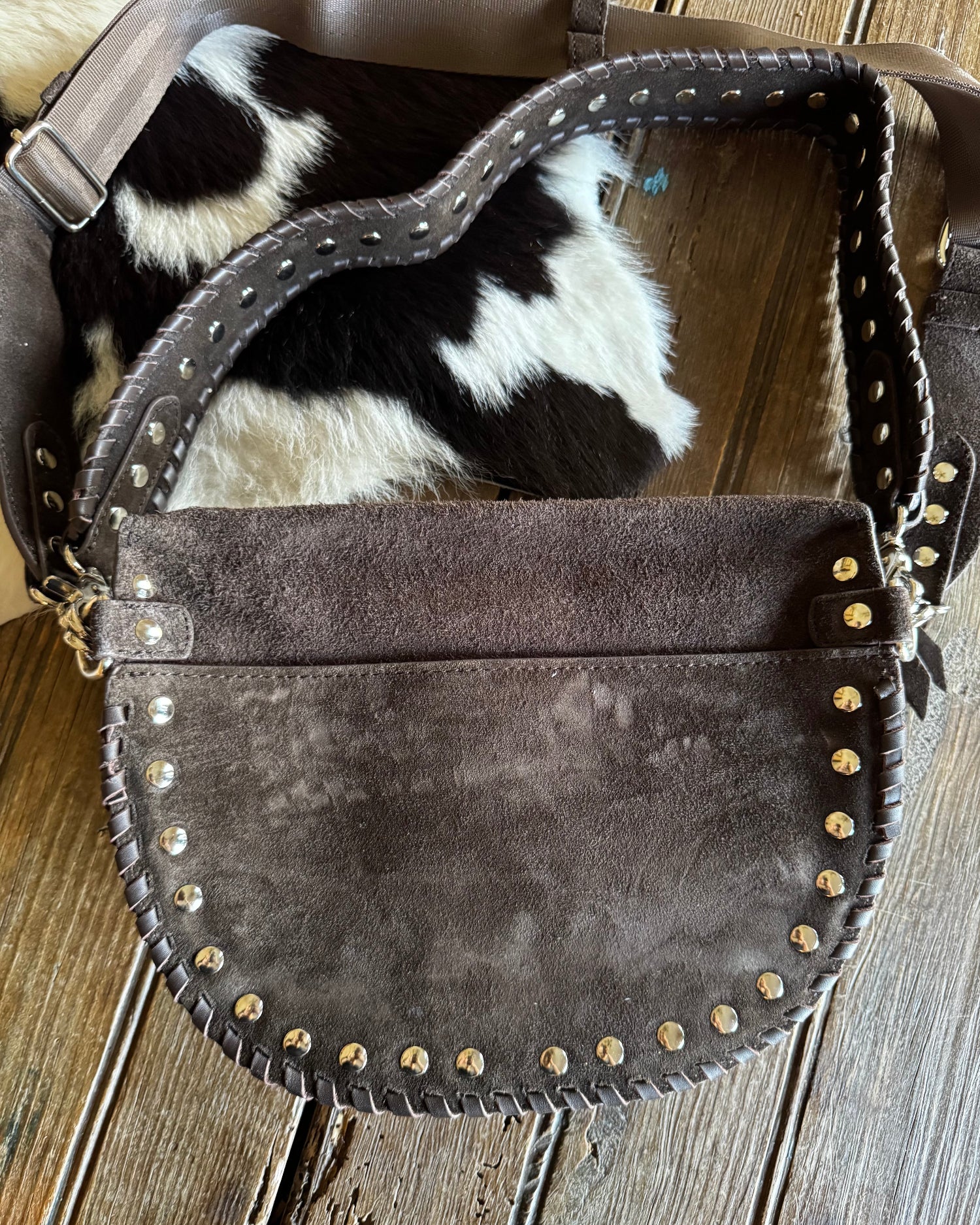 Brown leather bag with studs on a wooden surface