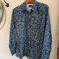 Blue patterned shirt on a hanger against a white wall
