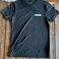 Black t-shirt with a brand logo on a wooden surface