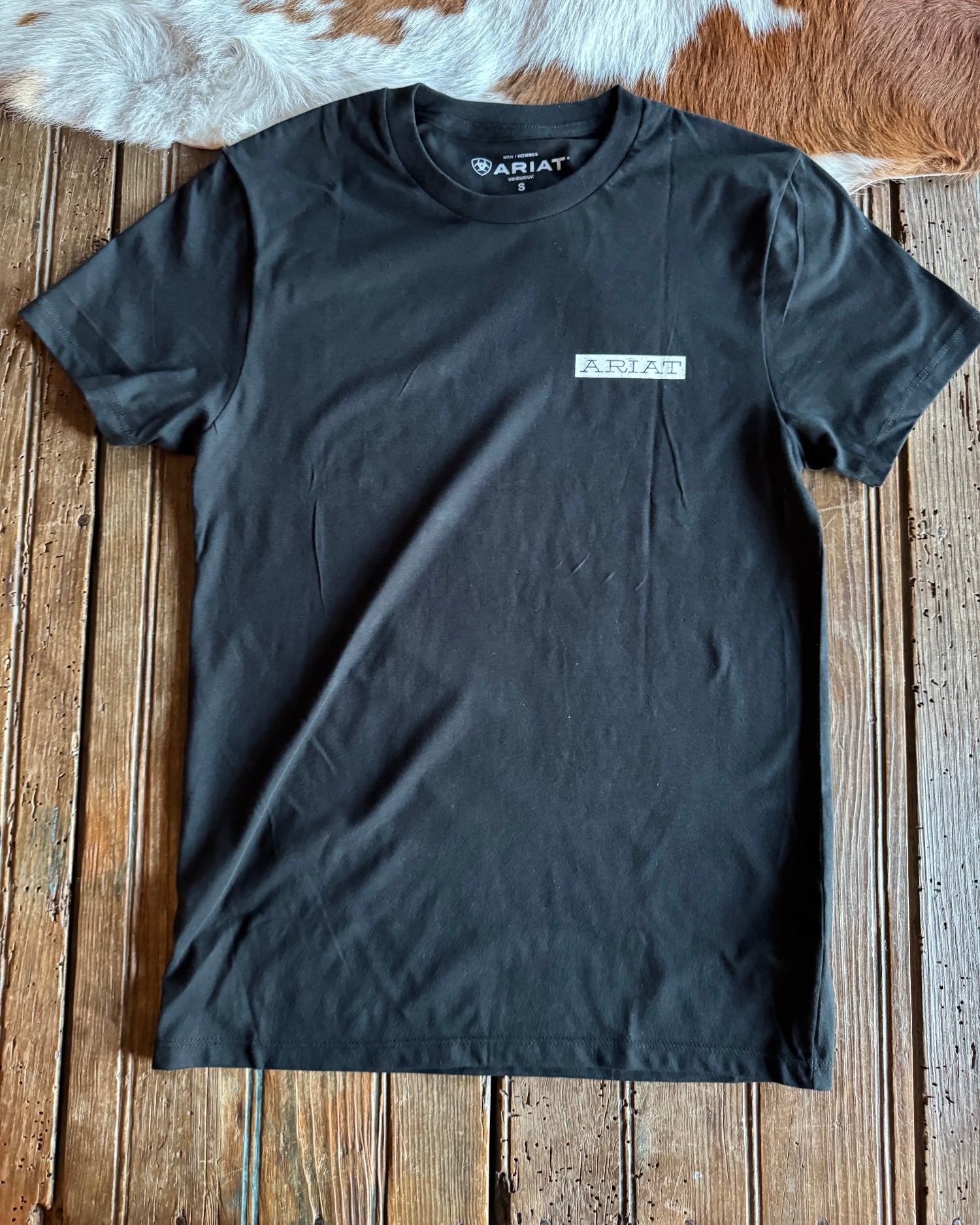 Black t-shirt with a brand logo on a wooden surface