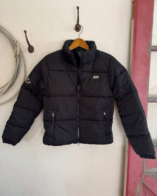 Black puffer jacket on a white surface with tools in the background