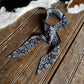 Patterned bow tie on a wooden surface with a cowhide rug in the background