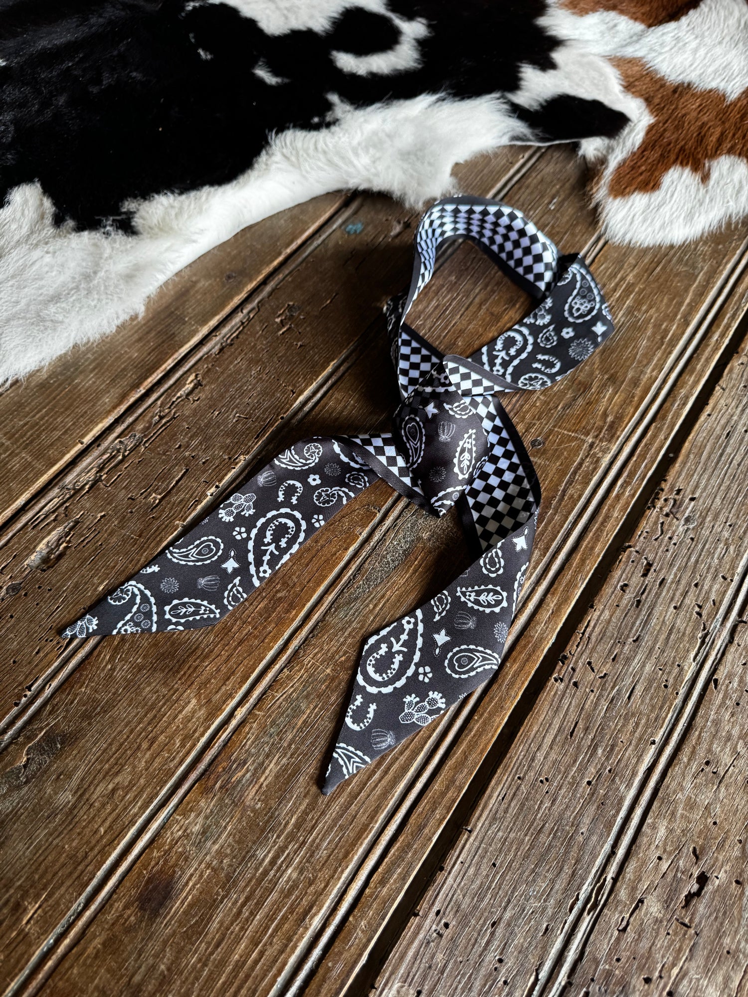Patterned bow tie on a wooden surface with a cowhide rug in the background