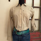 Person wearing a beige shirt and blue jeans standing against a red and white wall.