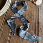Decorative ribbon scarf with turquoise concho pattern on a wooden surface