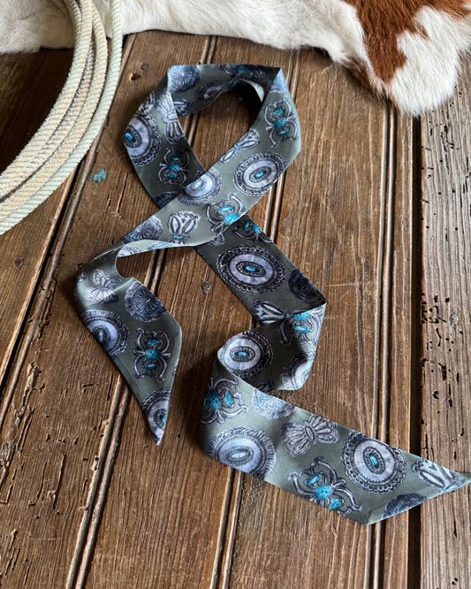 Decorative ribbon scarf with turquoise concho pattern on a wooden surface