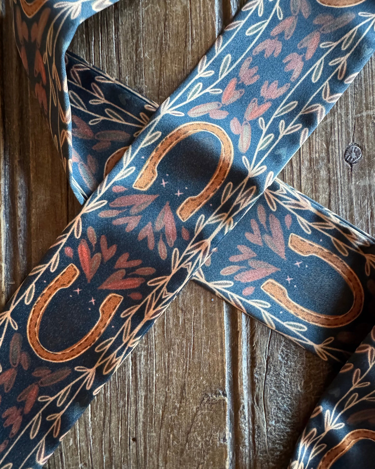 close up of horseshoe ribbon scarf on rustic wood background 
