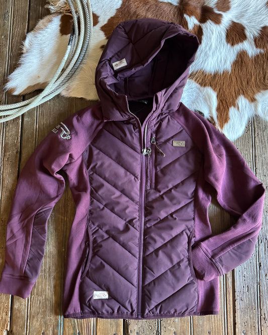 Purple quilted jacket on a wooden surface with a cowhide rug in the background