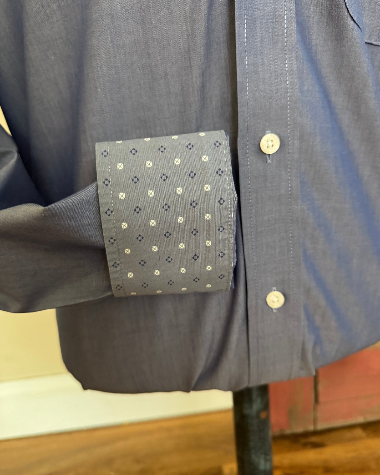 Close-up of a blue shirt with a patterned patch on a wooden surface
