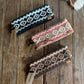 Three patterned headbands on a wooden surface with visible brand tags.