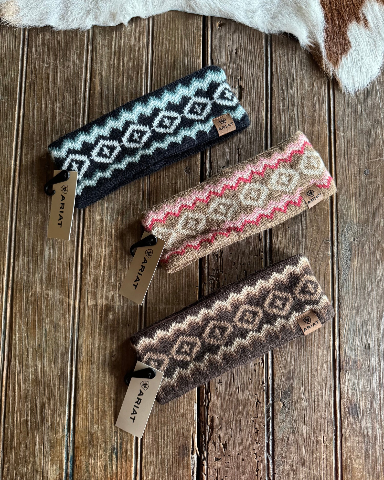 Three patterned headbands on a wooden surface with visible brand tags.