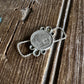 Silver pendant on a textured wooden surface with white fur