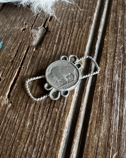 Silver pendant on a textured wooden surface with white fur