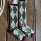 Green and white checkered sock with maroon accents on a wooden surface
