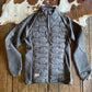 Gray quilted jacket on a wooden surface with cowhide rug