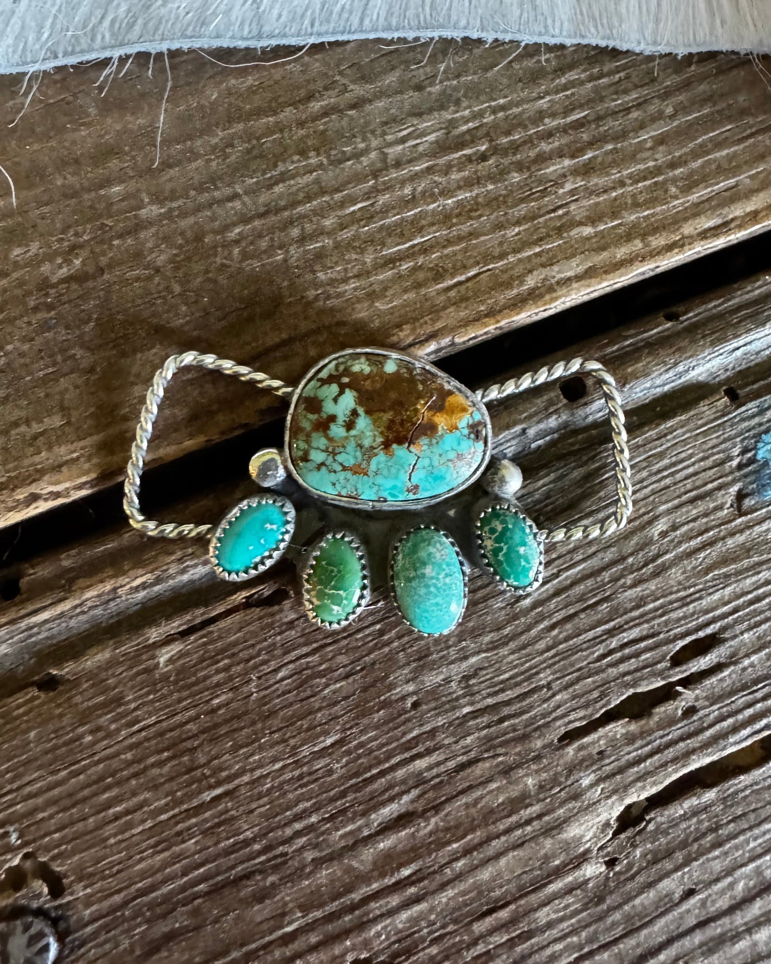 Turquoise stone brooch on a wooden surface