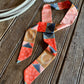 Quilt patchwork twilly scarf on a rustic wooden background with a cowhide and a rope