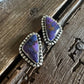 Pair of purple stone earrings on a wooden surface
