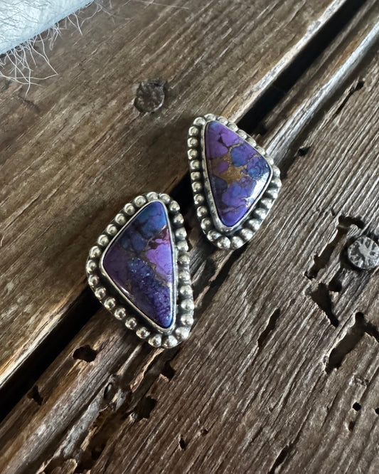 Pair of purple stone earrings on a wooden surface