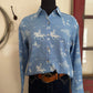 Blue shirt with white patterns on a mannequin against a neutral wall.