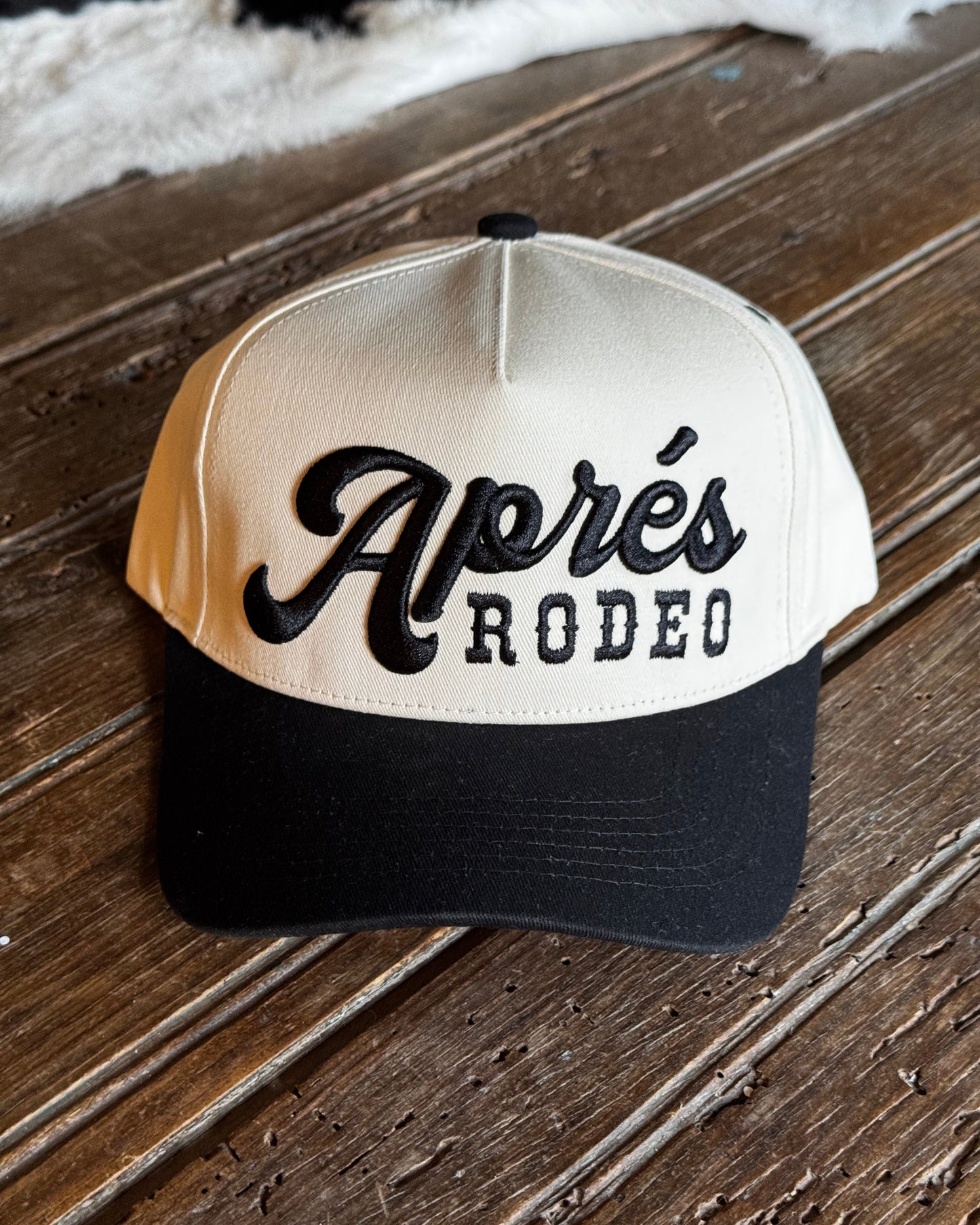 Cap with 'Aperés Rodeo' logo on a wooden surface