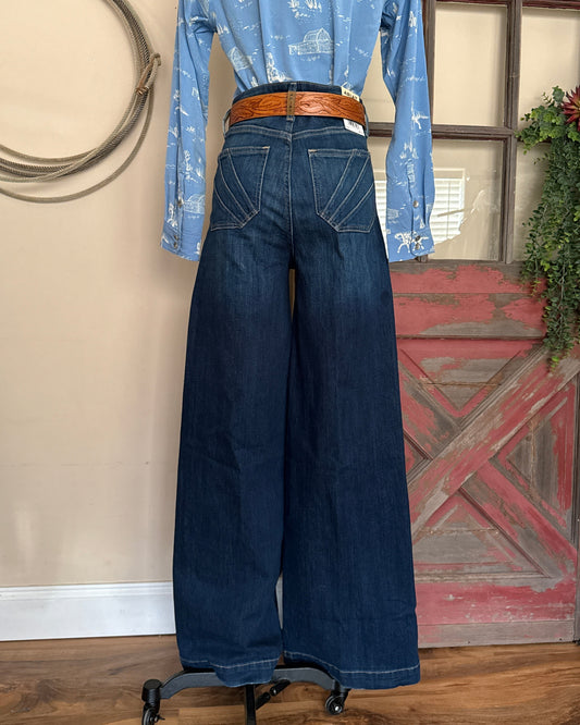 Blue jeans on a mannequin with a red barn door in the background