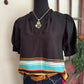Black blouse with colorful stripes on a mannequin against a neutral background