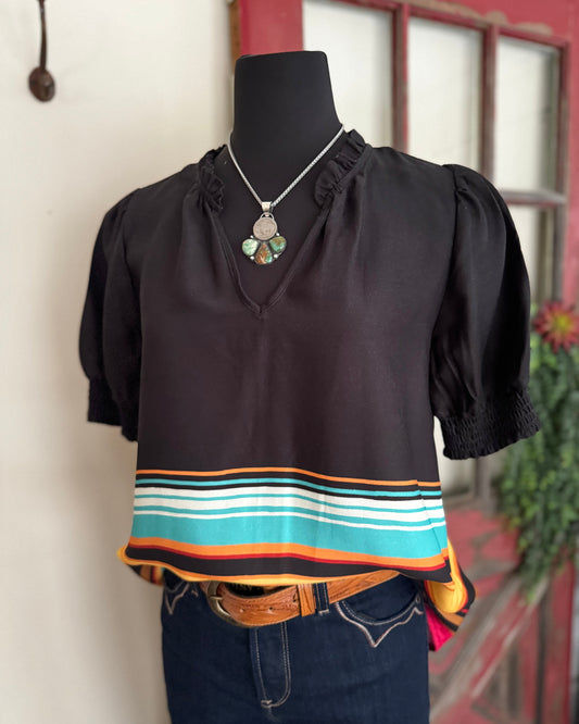 Black blouse with colorful stripes on a mannequin against a neutral background