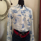 Mannequin wearing a white shirt with blue patterns and dark jeans against a neutral background
