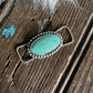 Turquoise stone ring on a wooden surface with white fur