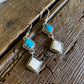 Pair of earrings with turquoise stones on a wooden surface