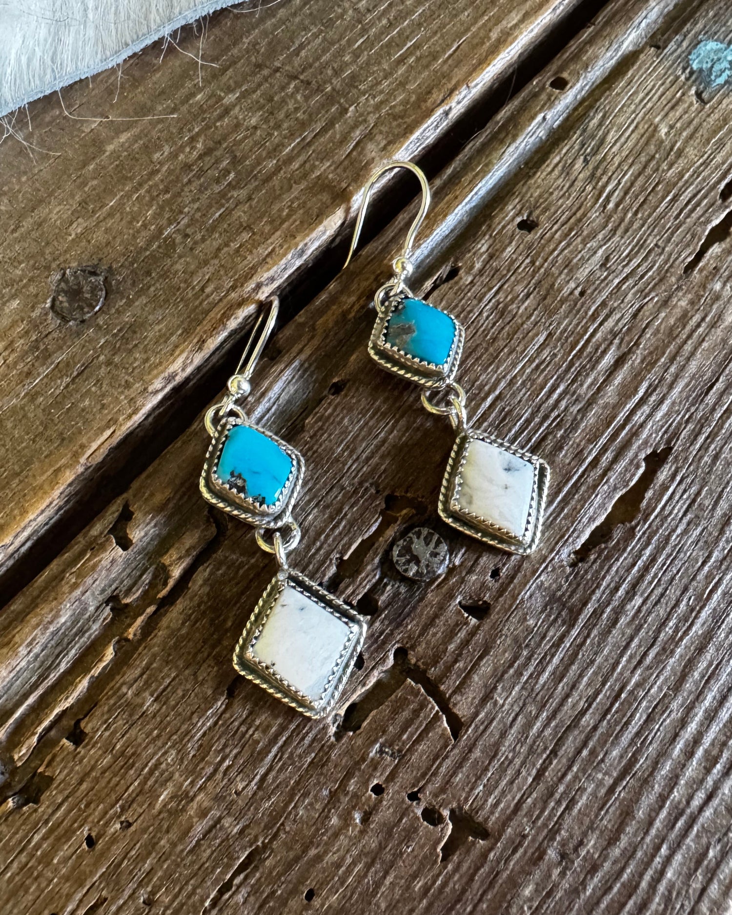 Pair of earrings with turquoise stones on a wooden surface
