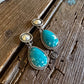 Turquoise earrings with silver accents on a wooden surface