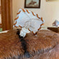 A close-up of a brown and black fur pelt with a small white plastic light fixture wrapped in tan cord, mounted on the fur.