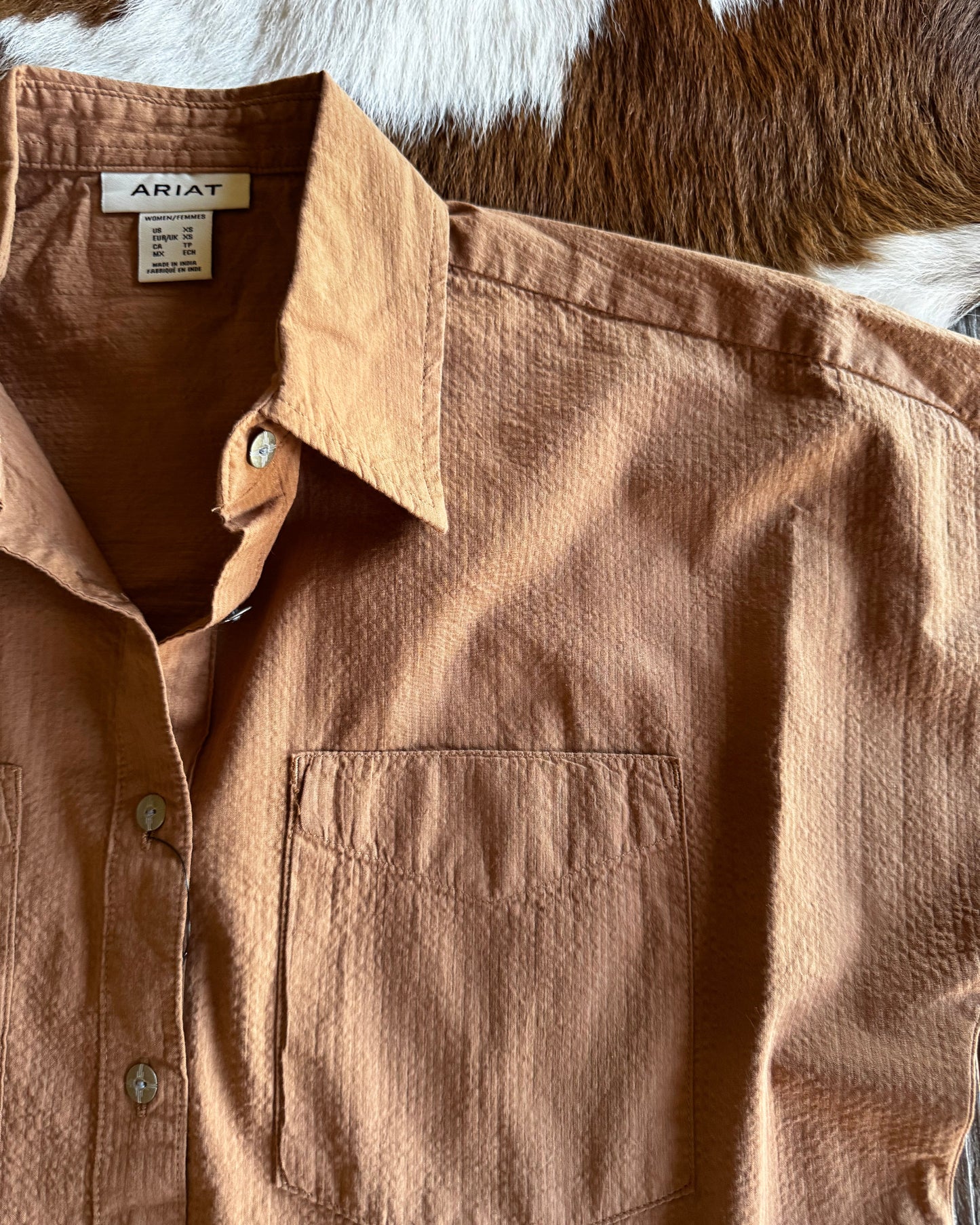 Brown shirt with a brand label on a textured surface