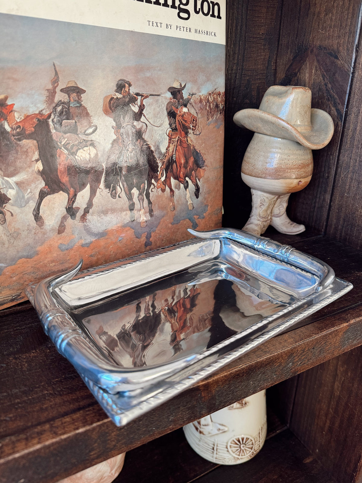 Silver tray on a wooden surface with a book and decorative items in the background