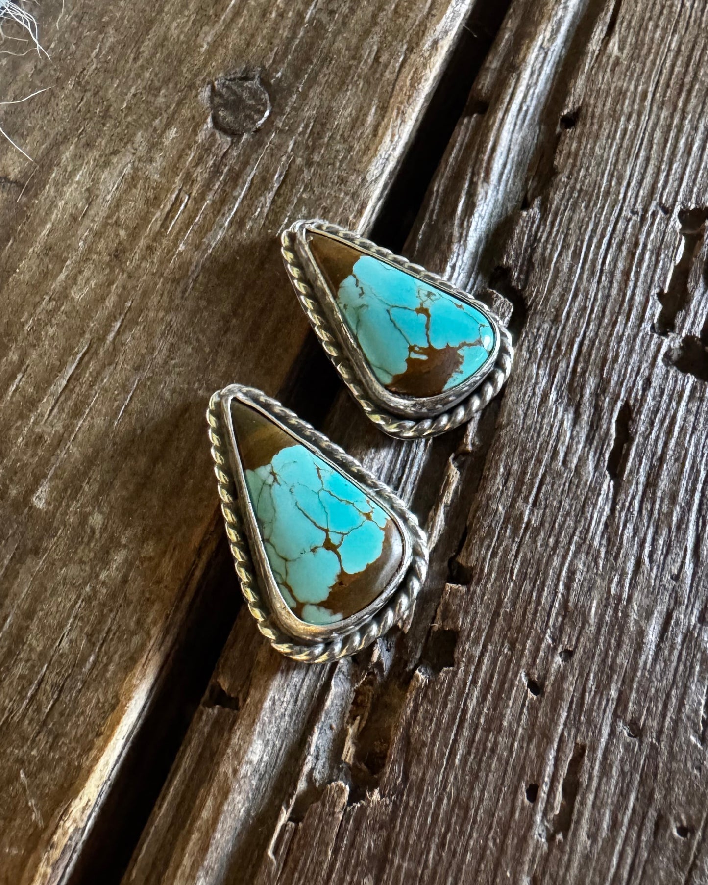 Turquoise stone earrings on a wooden surface