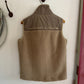 Brown vest with 'UNDOMESTICATED' branding on a white wall.