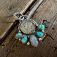 Pendant with coins and turquoise stones on a wooden surface