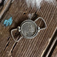 Silver twilly slide with a circular pendant on a wooden surface