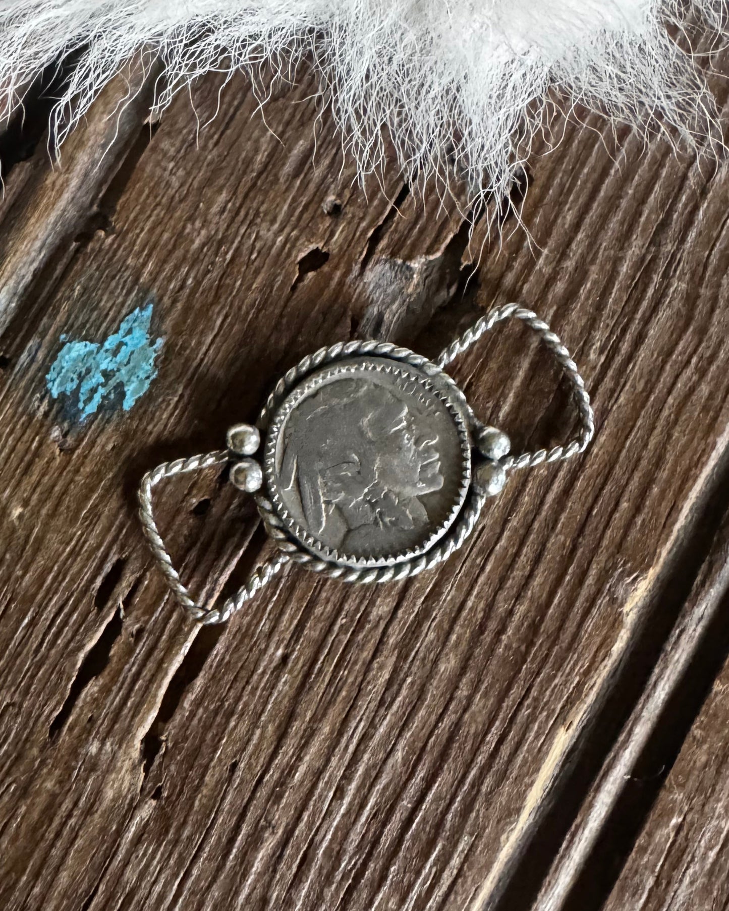 Silver twilly slide with a circular pendant on a wooden surface