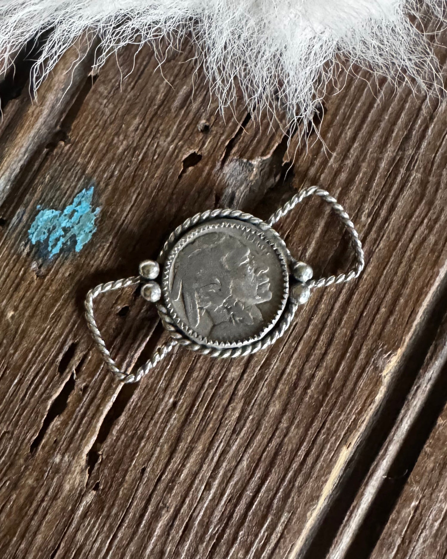 Silver twilly slide with a circular pendant on a wooden surface