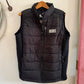 Black puffer vest on a hanger against a white wall